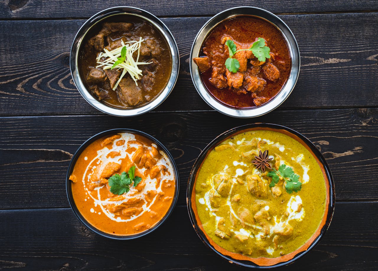 gallery-3 Vibrant Indian curries in bowls on a dark rustic table, ideal for food enthusiasts.