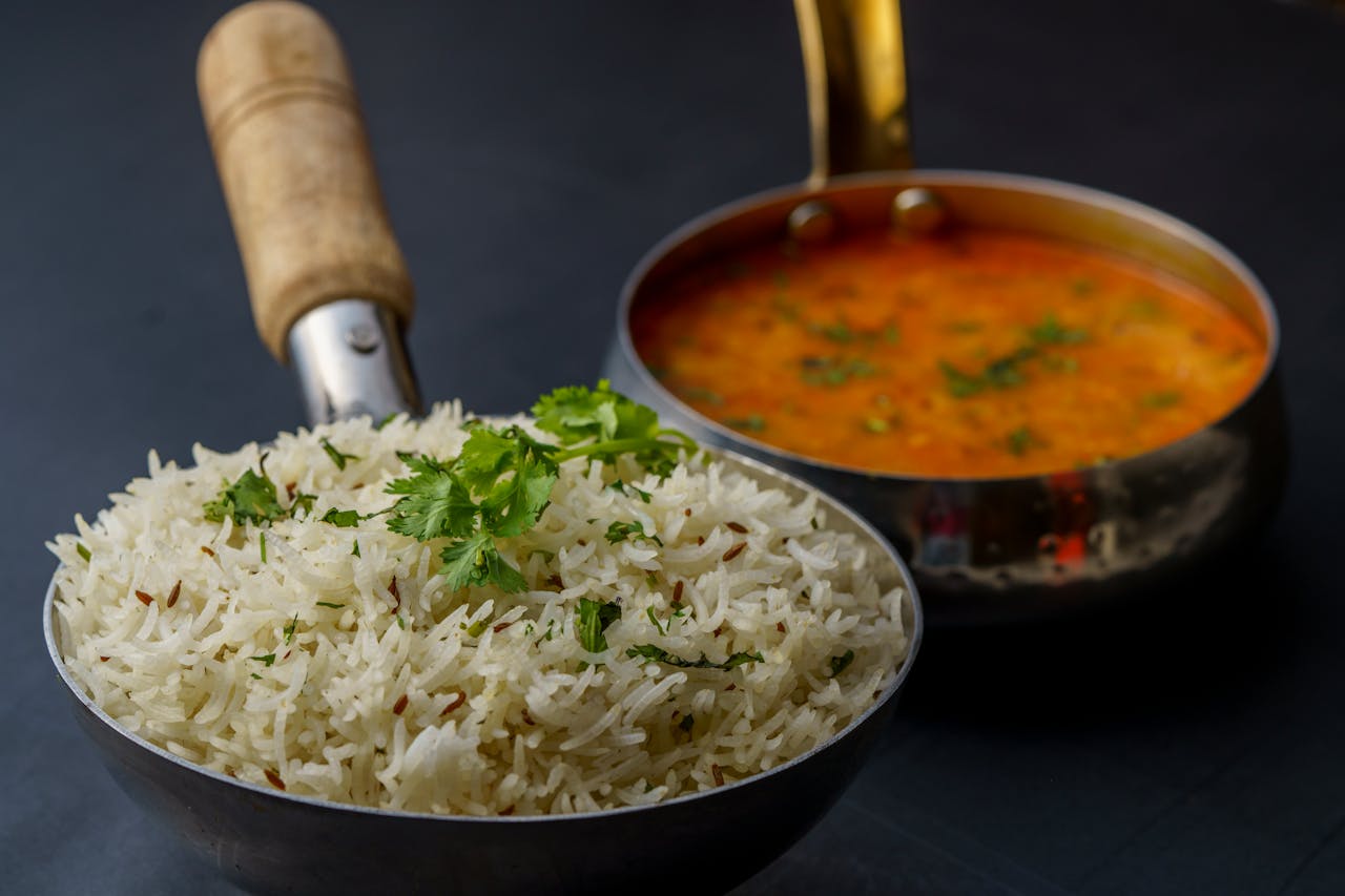 services-03 A savory dish of Indian dal with aromatic rice garnished with fresh cilantro, served in traditional utensils.