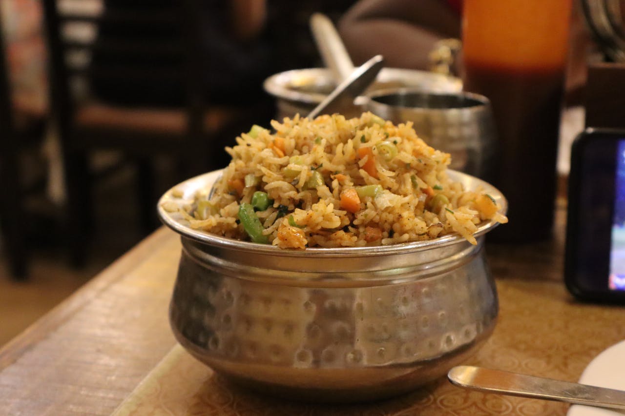 services-02 A flavorful serving of Indian fried rice with vegetables in a traditional metal bowl, ideal for food enthusiasts.