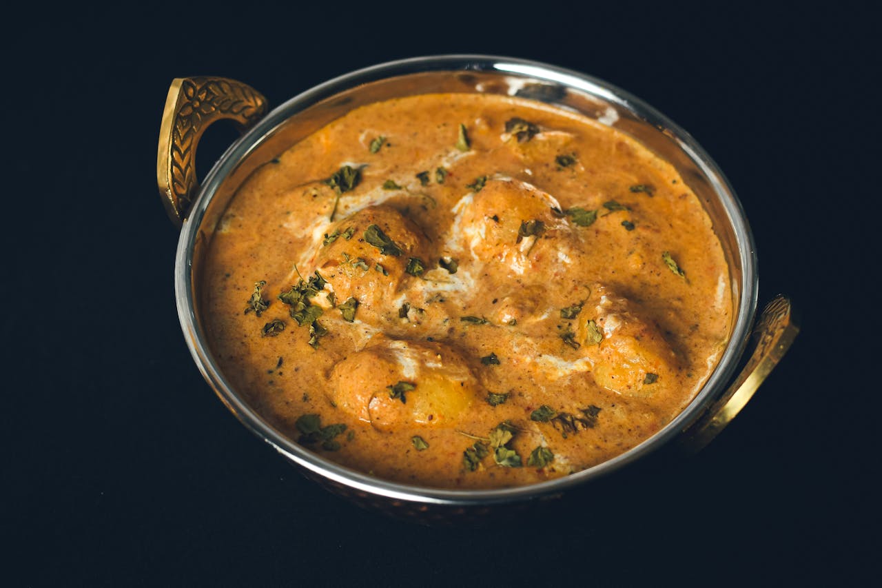 gallery-2 Delicious Dum Aloo curry served in a traditional Indian bowl, showcasing rich spices and fresh herbs.