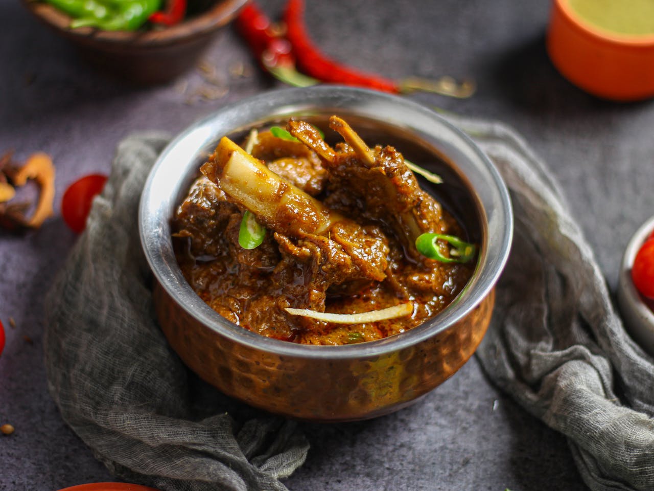 gallery-1 Close-up of a spicy mutton curry served in a traditional copper bowl, showcasing rich Indian flavors.